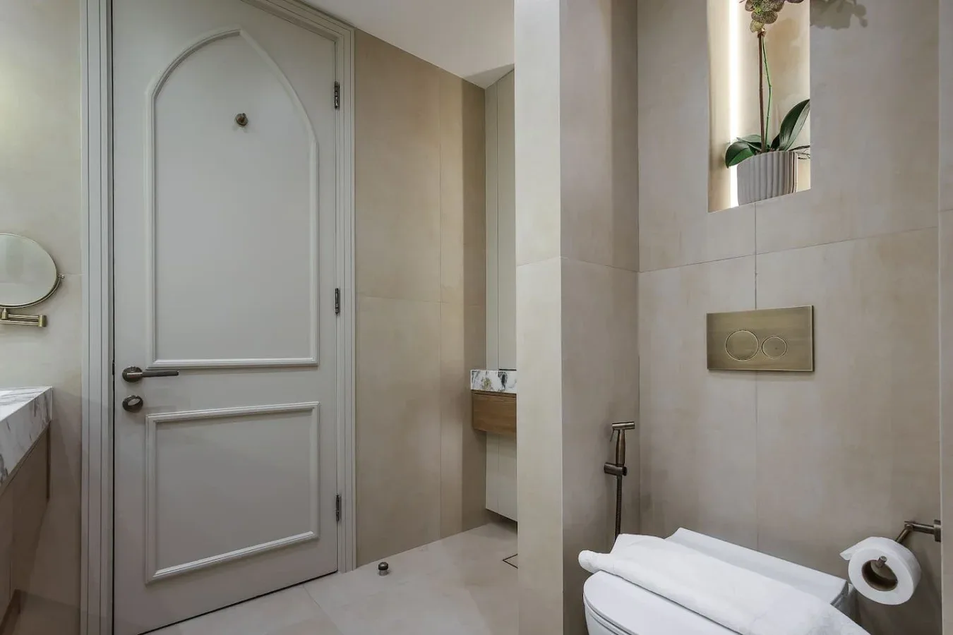 Un baño revestido de azulejos, con una puerta panelada, controles en la pared y un inodoro.