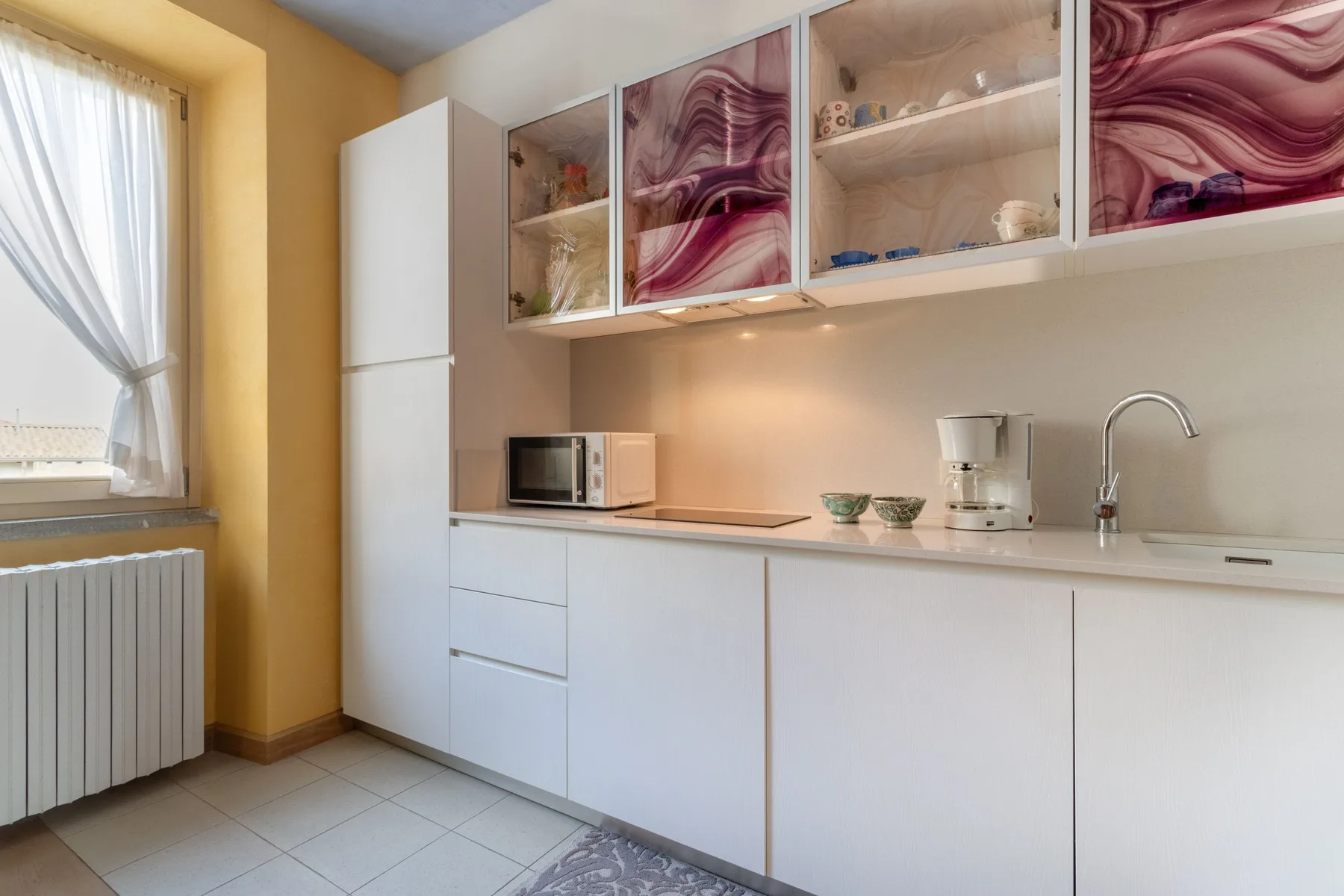 A bright kitchen with white cabinets, a countertop, and a window.