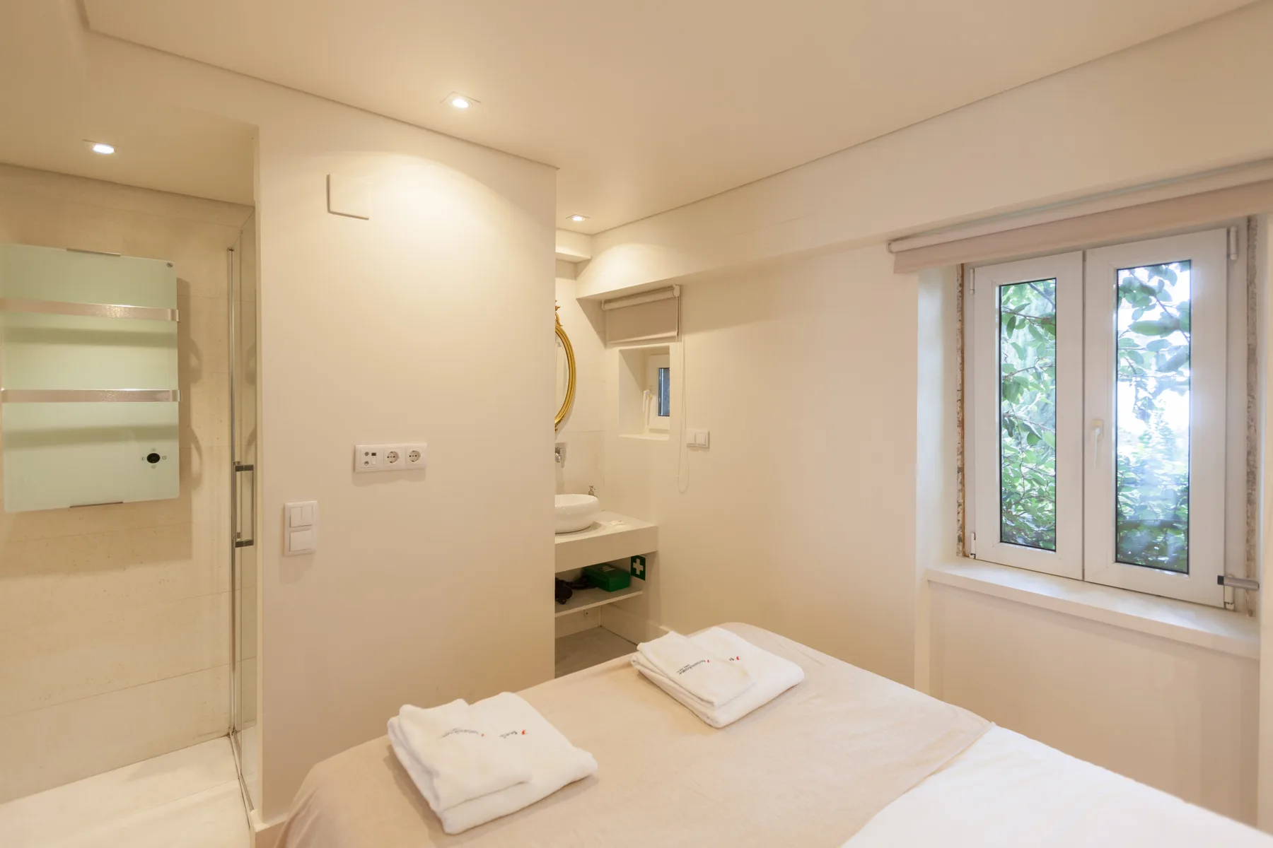 Un dormitorio luminoso con una cama bien tendida y una ventana.