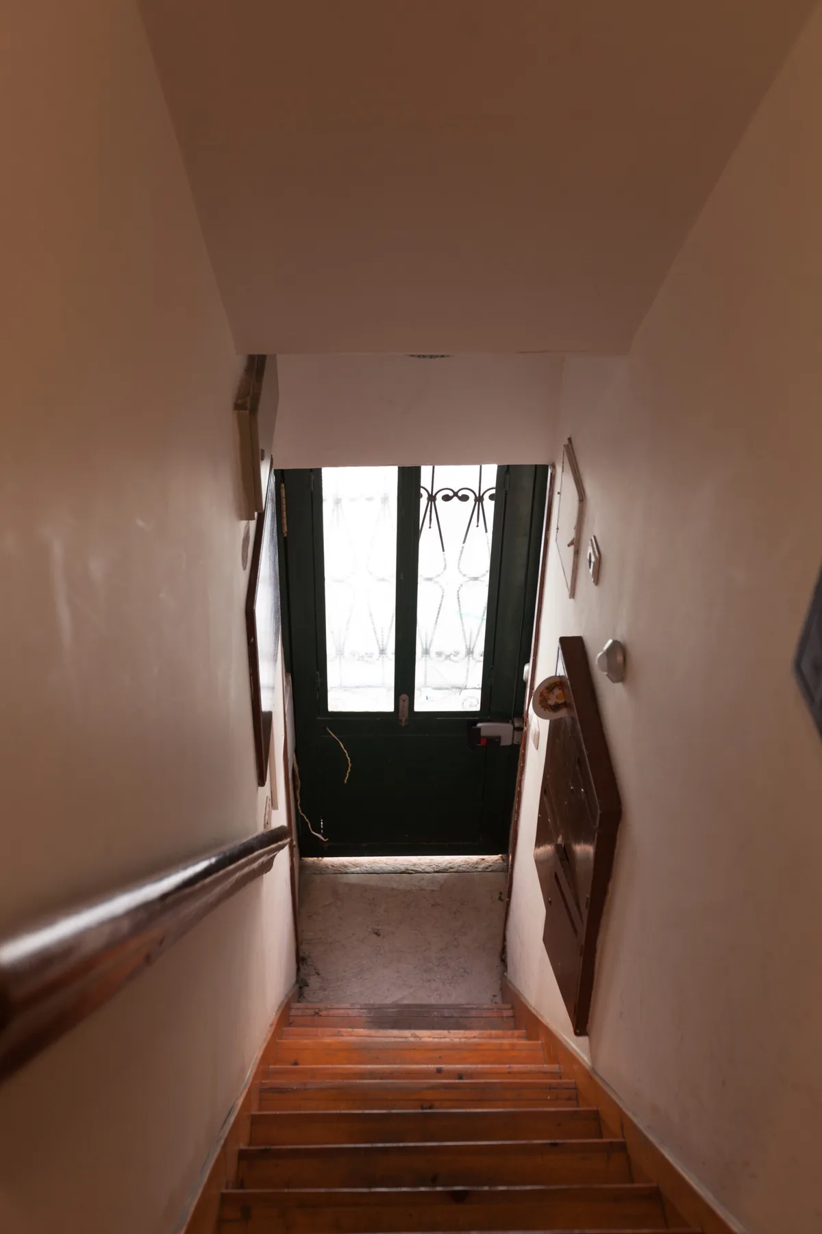 Una escalera interior desciende hacia una puerta oscura con paneles de vidrio.