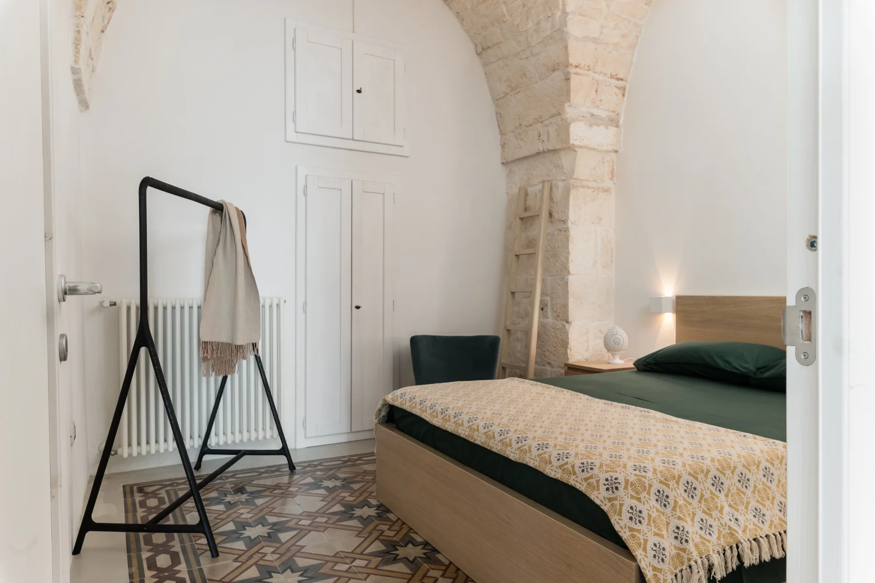 Un dormitorio con una colcha estampada y ropa de cama verde oscuro.