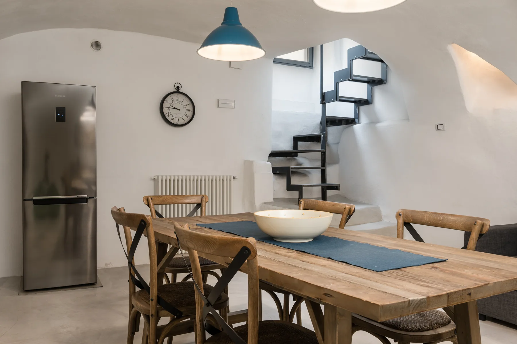 Un comedor con una mesa de madera y sillas está junto a una escalera.