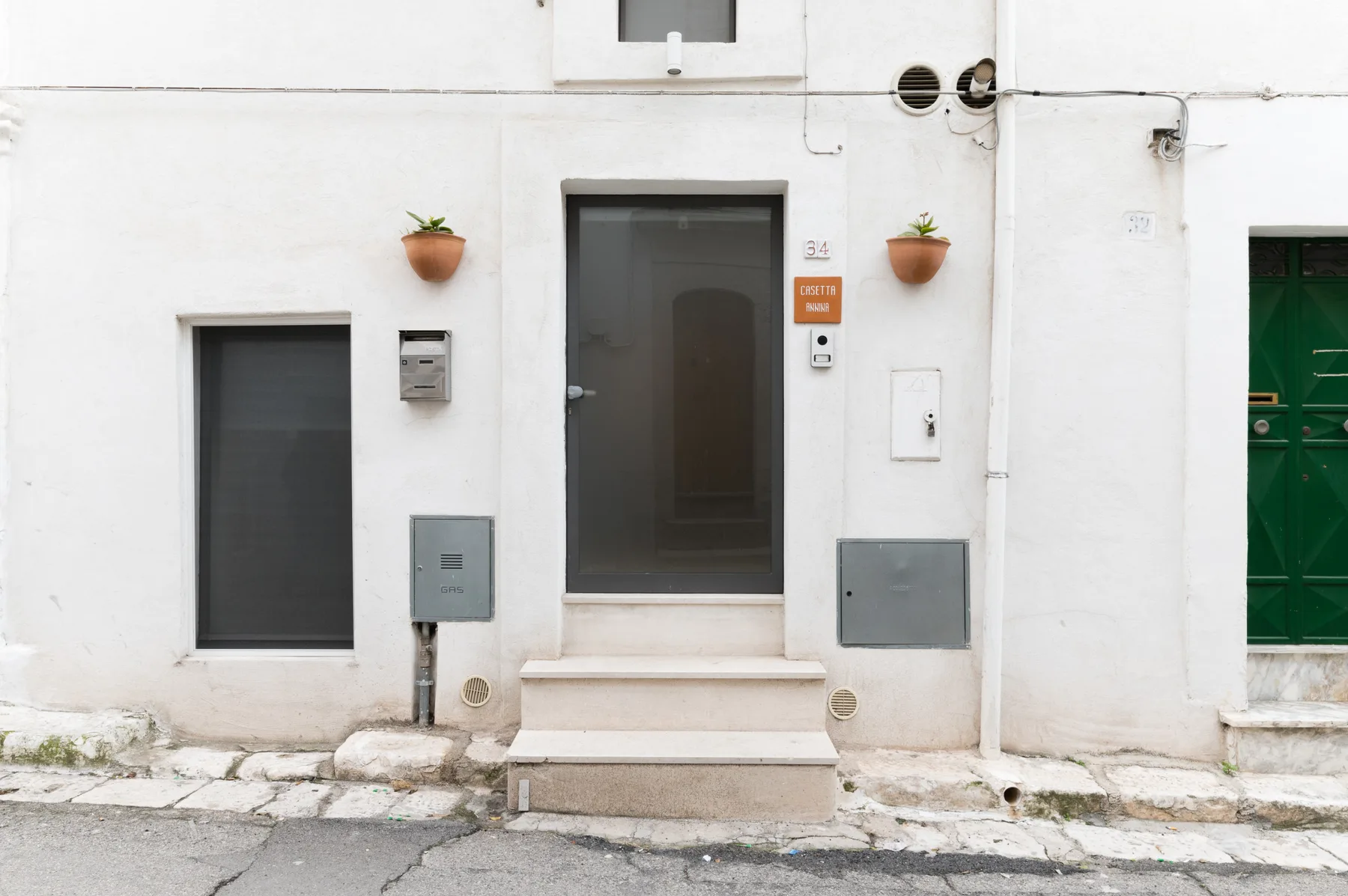Una fachada blanca con una puerta de entrada oscura y escalones bajos.