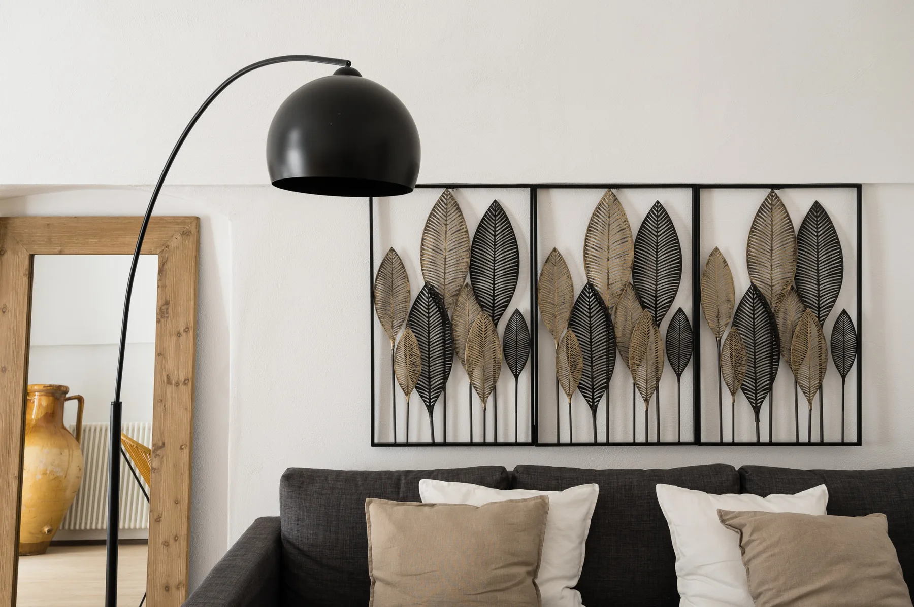 Una zona de estar con una obra enmarcada de hojas sobre el sofá.