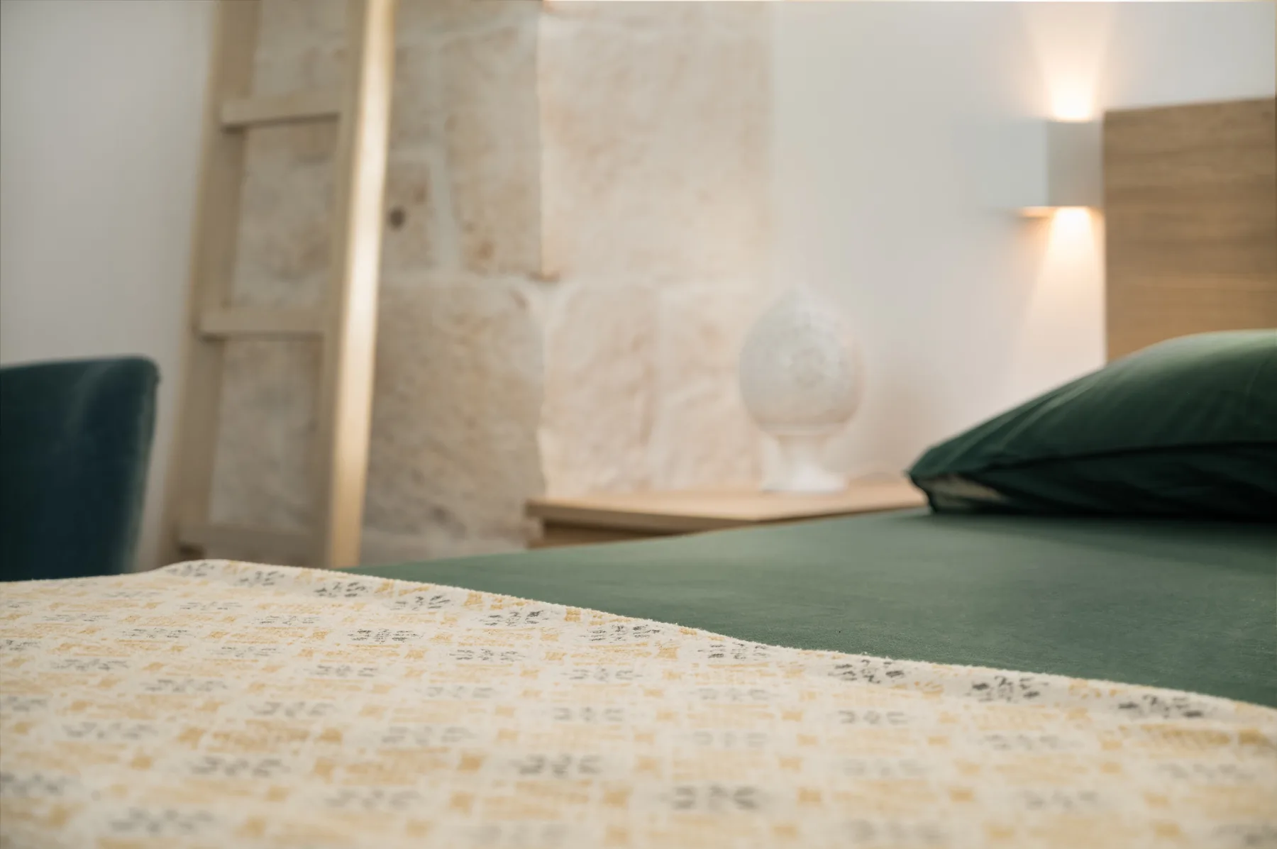 Un dormitorio con ropa de cama verde y una mesita junto a la cama.