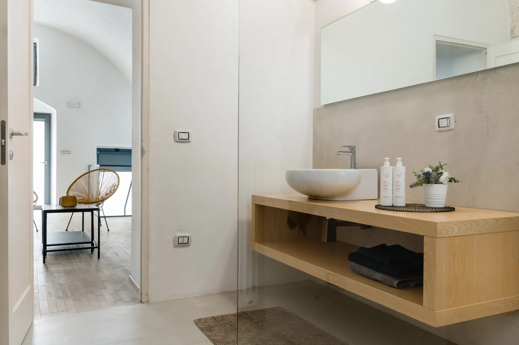 Un baño luminoso con un mueble de madera y un lavabo sobre encimera.