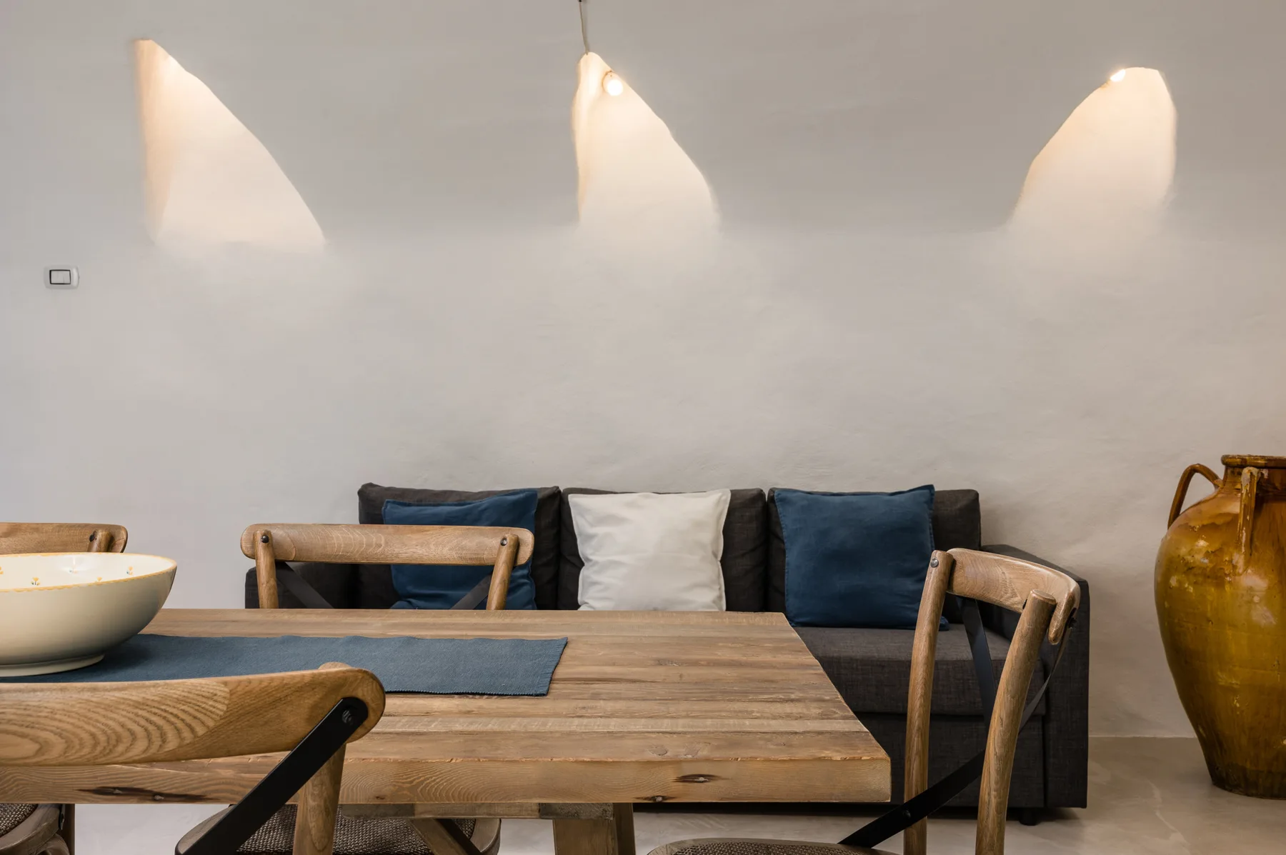 Comedor con una mesa de madera, asientos y tres luces de pared.