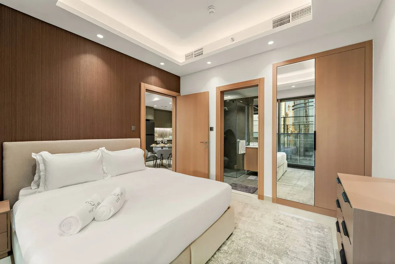 Un dormitorio con una cama bien arreglada y puertas de armario con espejo.