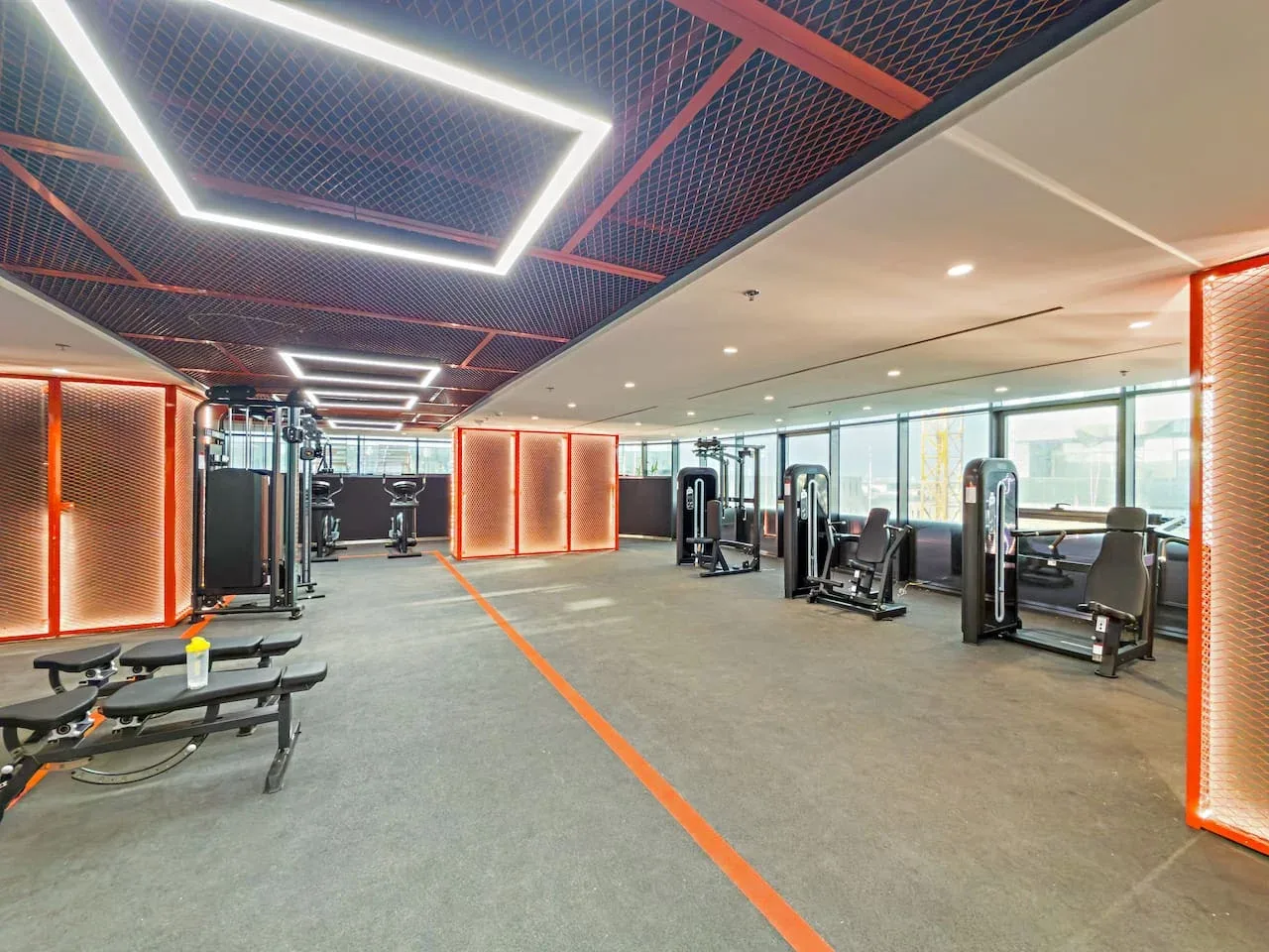 Un gimnasio con máquinas de ejercicio y bancos de pesas distribuidos en un espacio abierto.