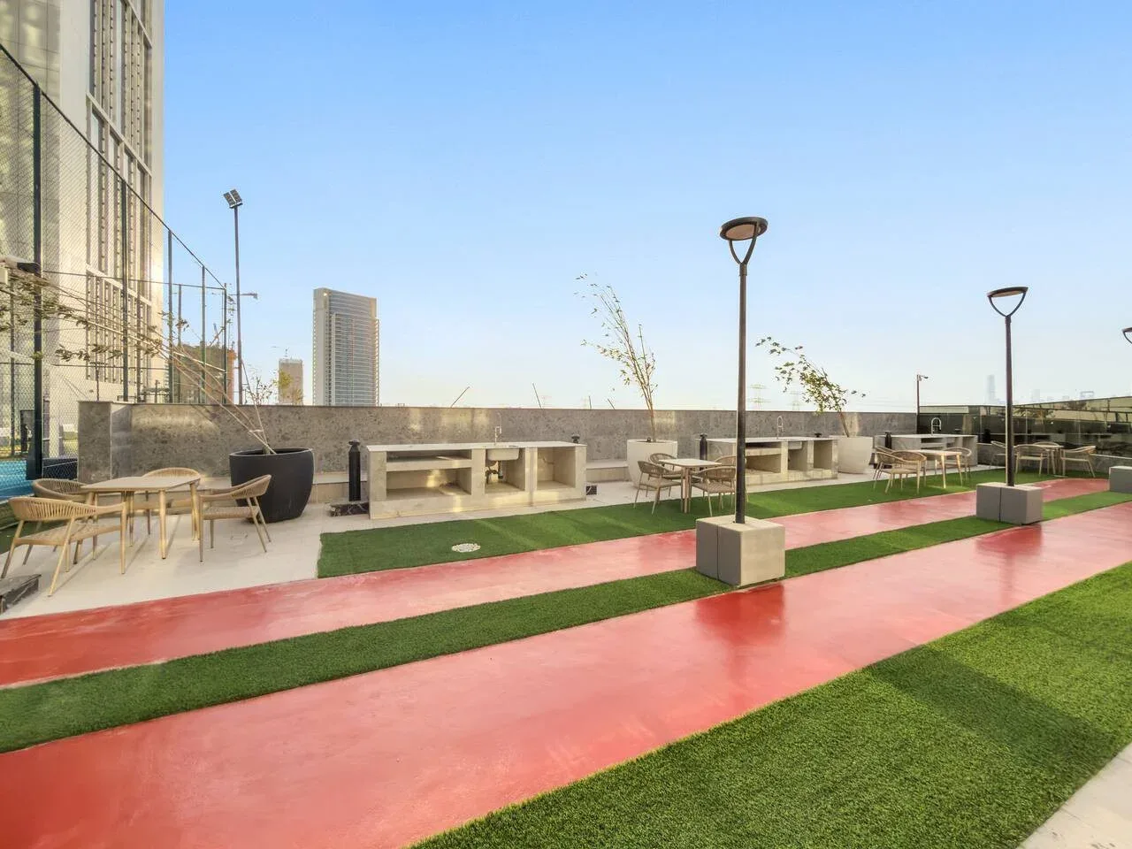 Una zona recreativa al aire libre tiene carriles rojos, césped artificial y asientos.