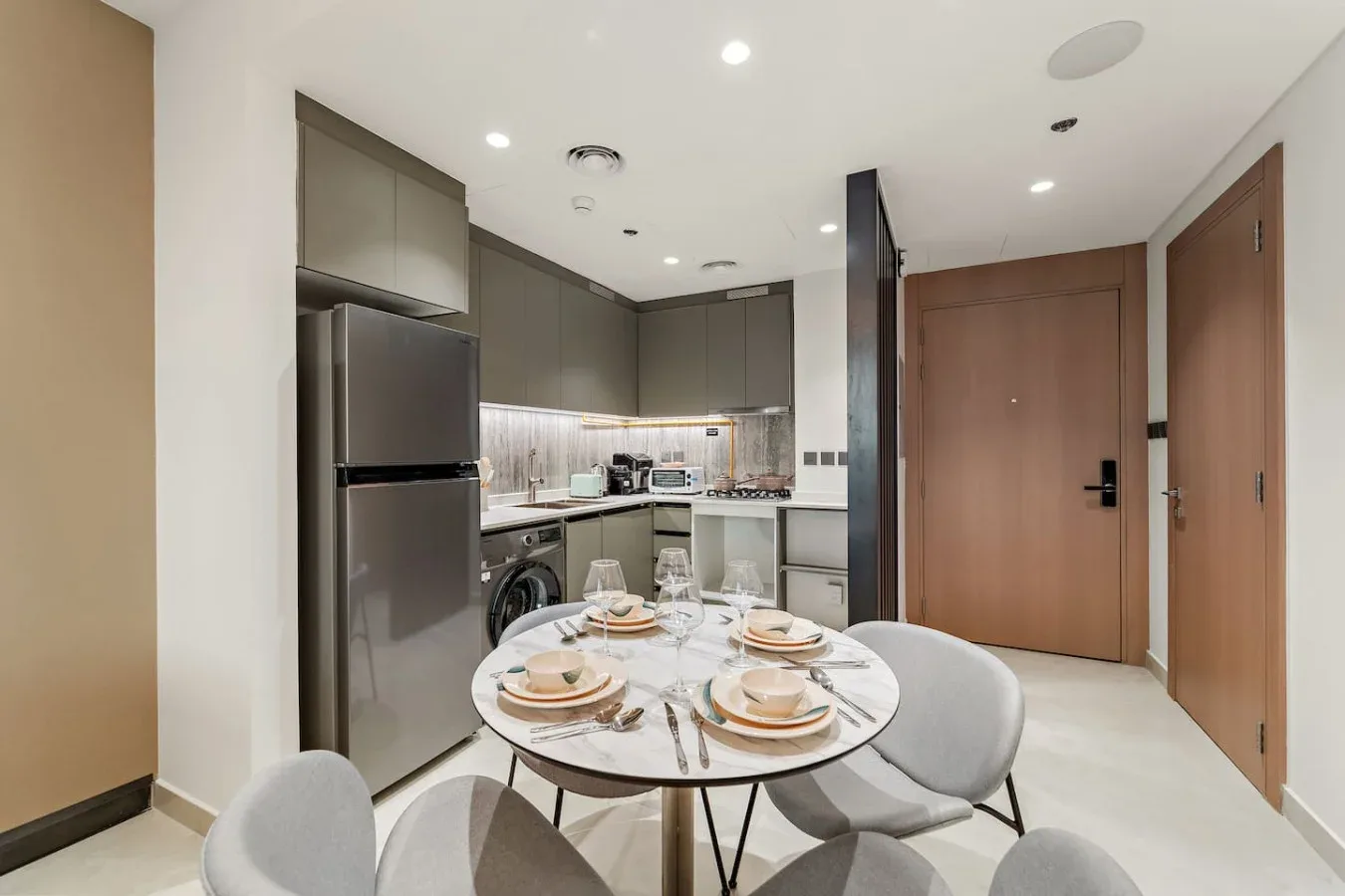 Un comedor con una mesa redonda está junto a una cocina compacta.