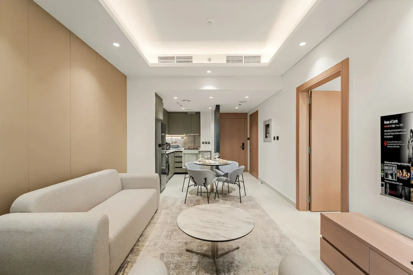 Una sala de estar moderna con asientos, una mesa de comedor y una cocina al fondo.