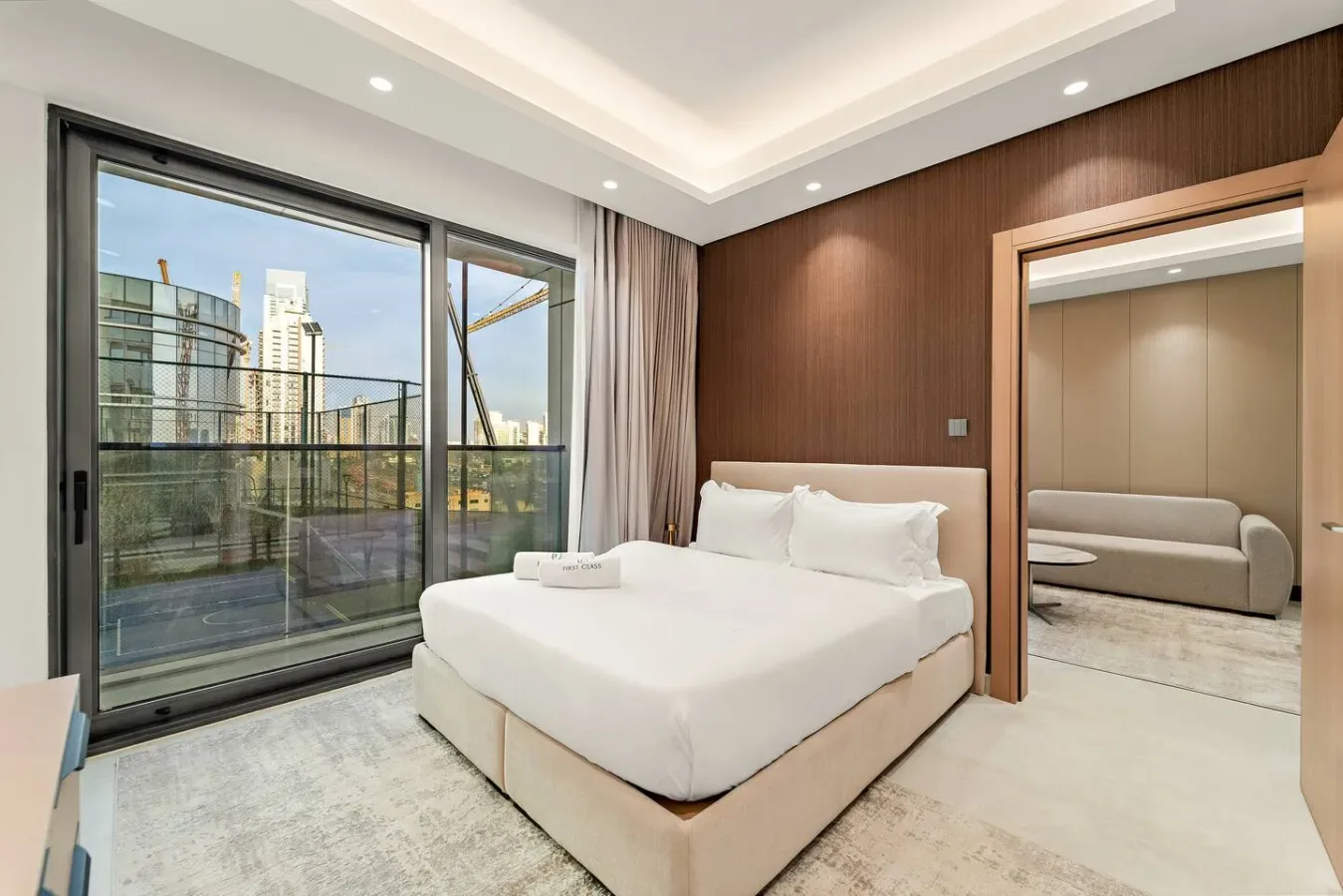 Dormitorio con una cama blanca junto a grandes puertas de vidrio que dan a un balcón.