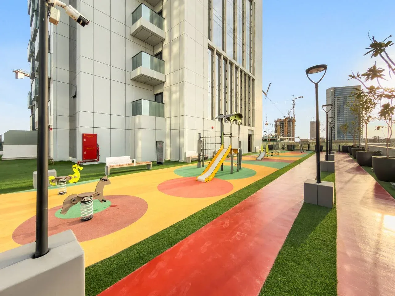 Un parque infantil colorido al aire libre junto a un edificio moderno de gran altura.