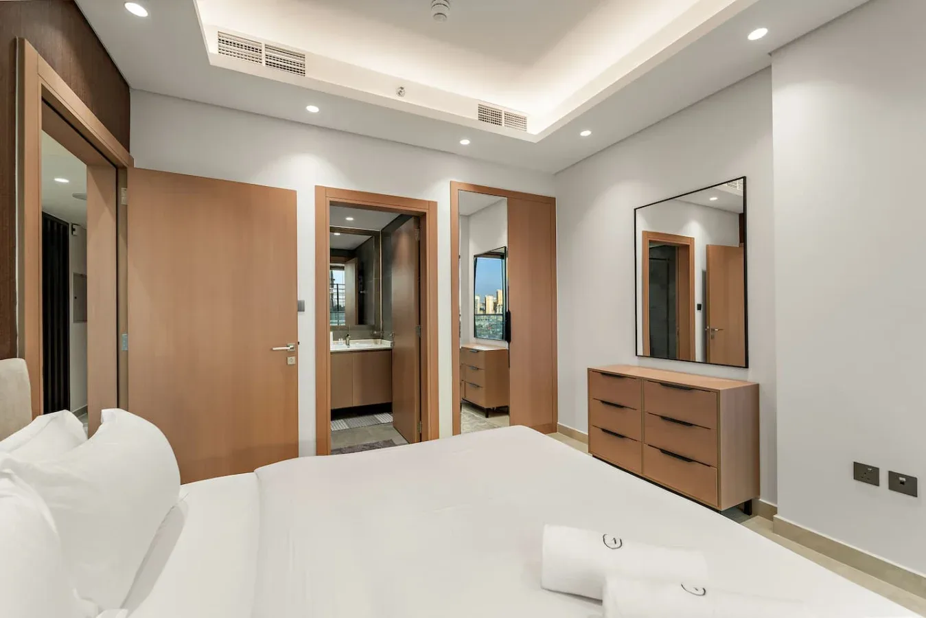 Un dormitorio con una cama, puertas de madera y una cómoda bajo un espejo.
