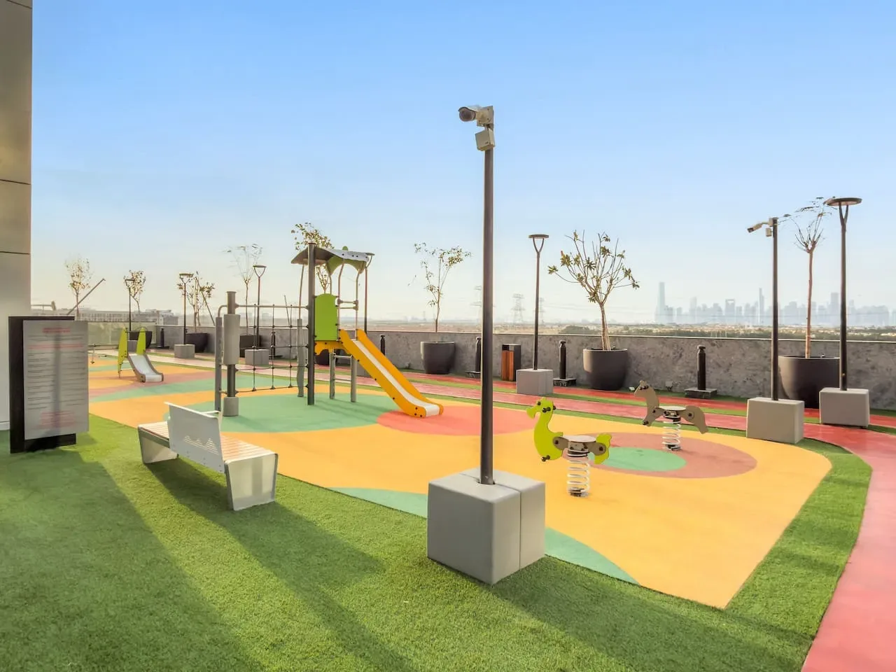 Un parque infantil en una azotea con suelo colorido, un tobogán y estructuras para trepar.