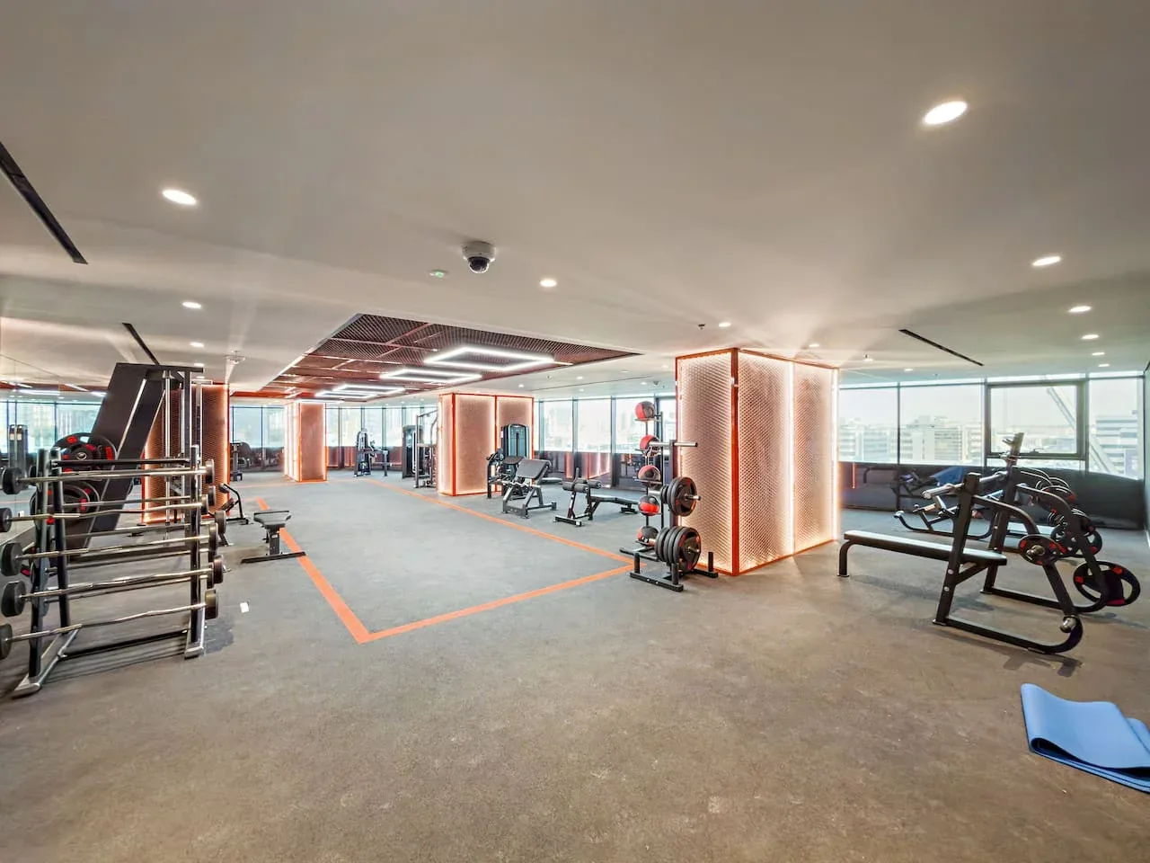 Un gimnasio amplio con máquinas de ejercicio y grandes ventanales.