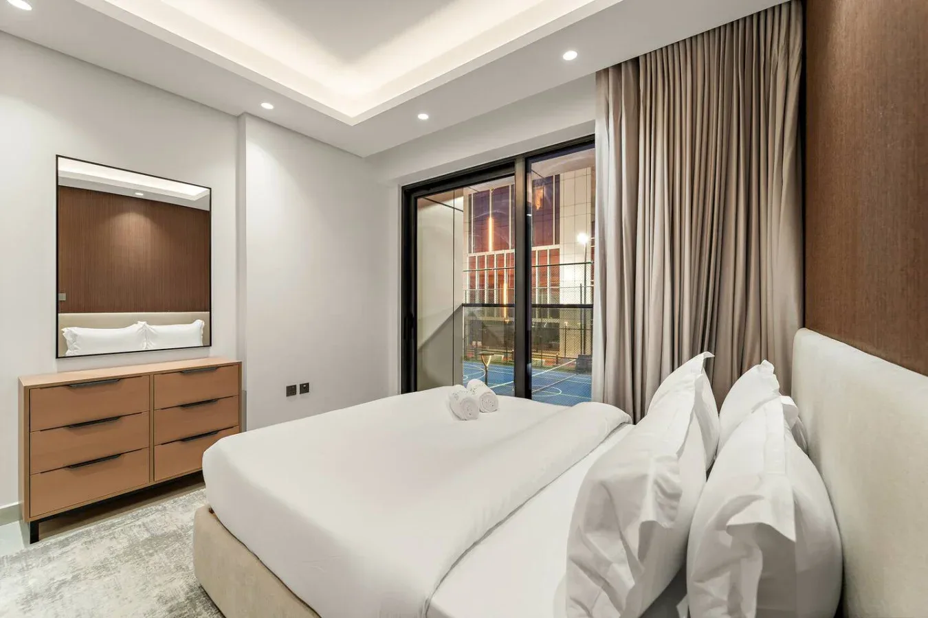 Un dormitorio con una cama bien arreglada y puertas de vidrio que dan a un balcón.