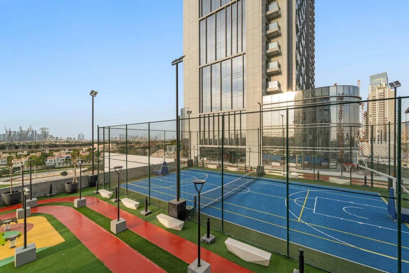 Las canchas deportivas al aire libre, con superficies azules, están junto a un edificio moderno alto.