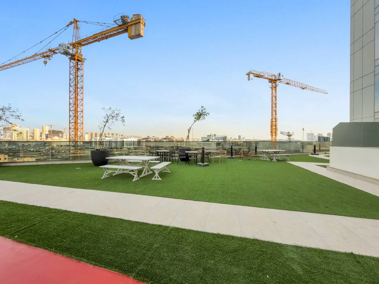 Una terraza exterior con césped artificial verde y asientos bajo un cielo despejado.