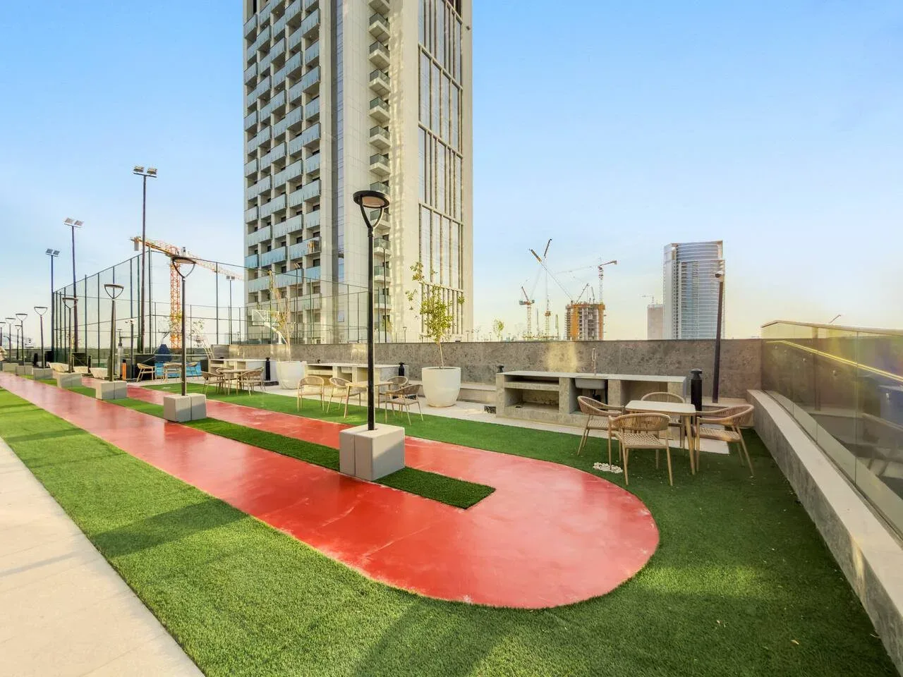 Una zona recreativa en la azotea tiene una pista roja, césped artificial y asientos al aire libre.