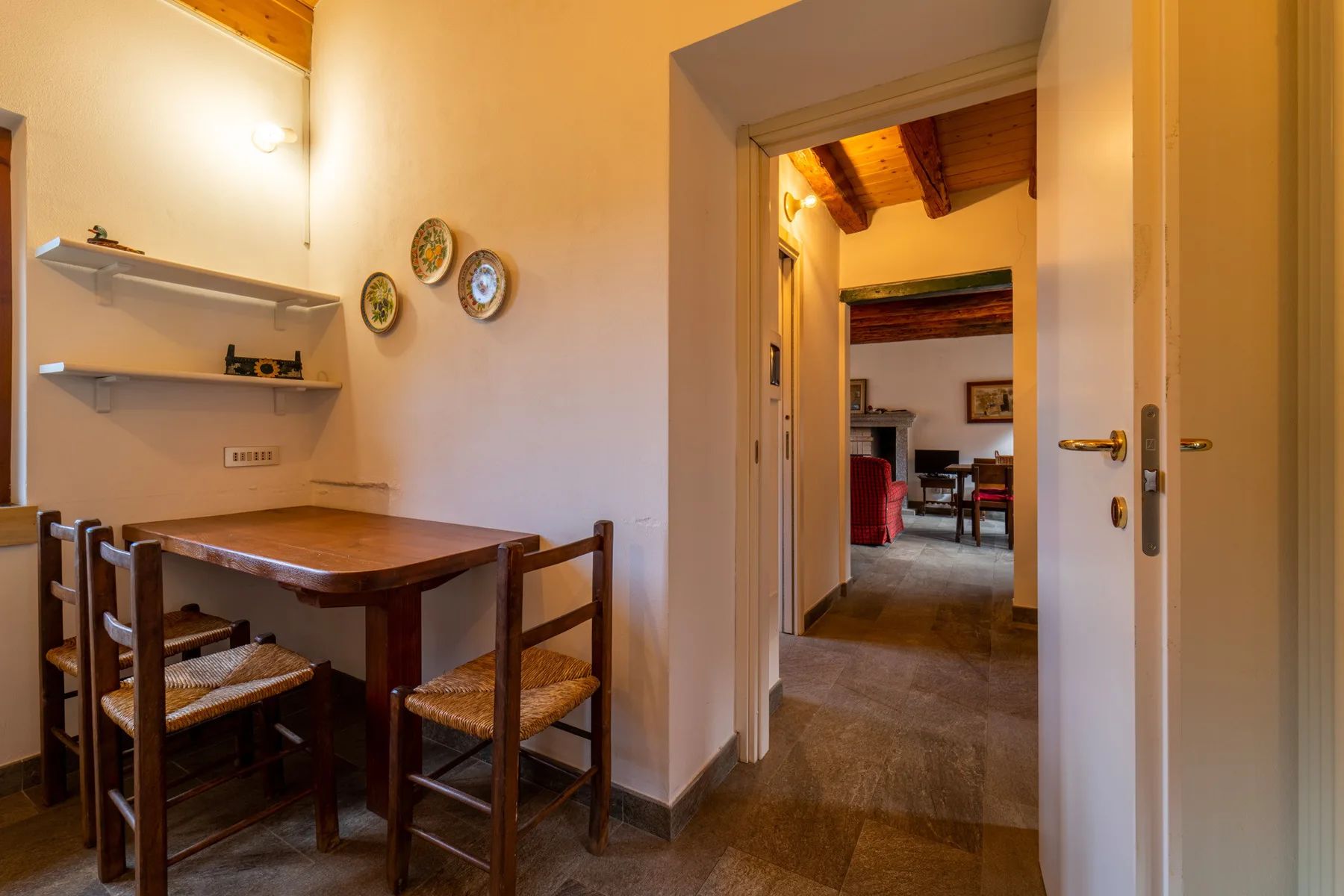 A dining area with a wooden table and chairs beside an open doorway.