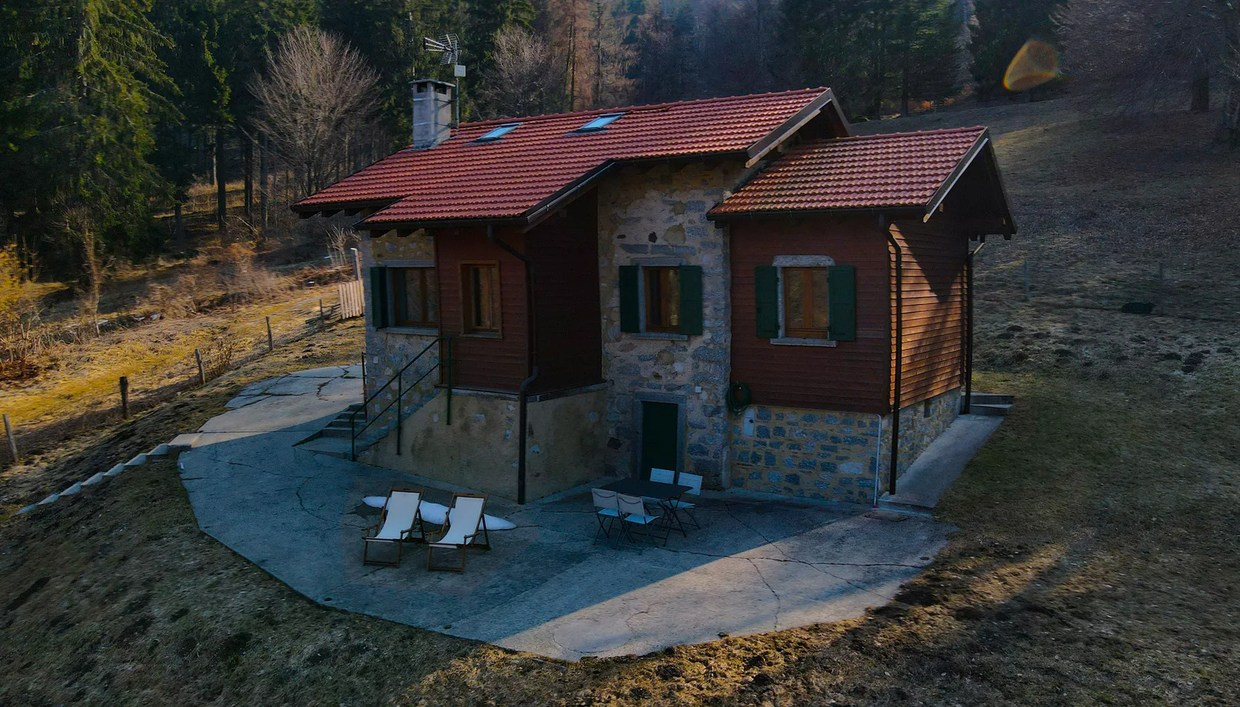 A detached house with a red tiled roof stands beside a curved paved area.