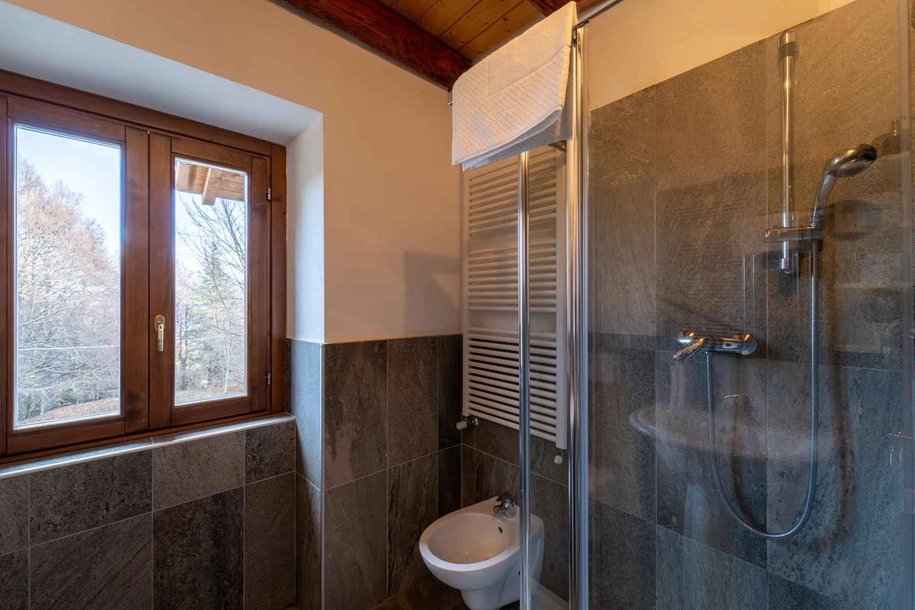 A tiled bathroom with a glass shower and a window.
