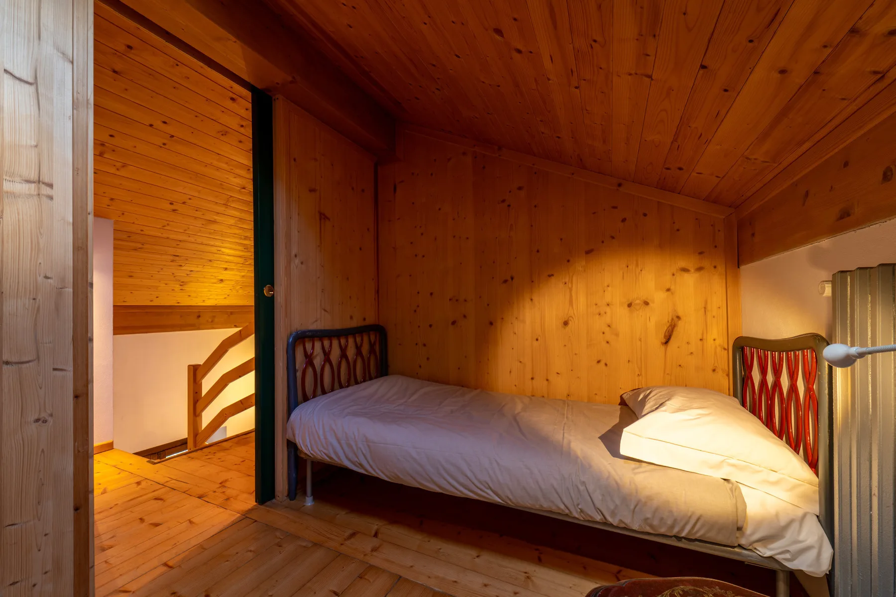 A wood-paneled bedroom with a bed and an open doorway.