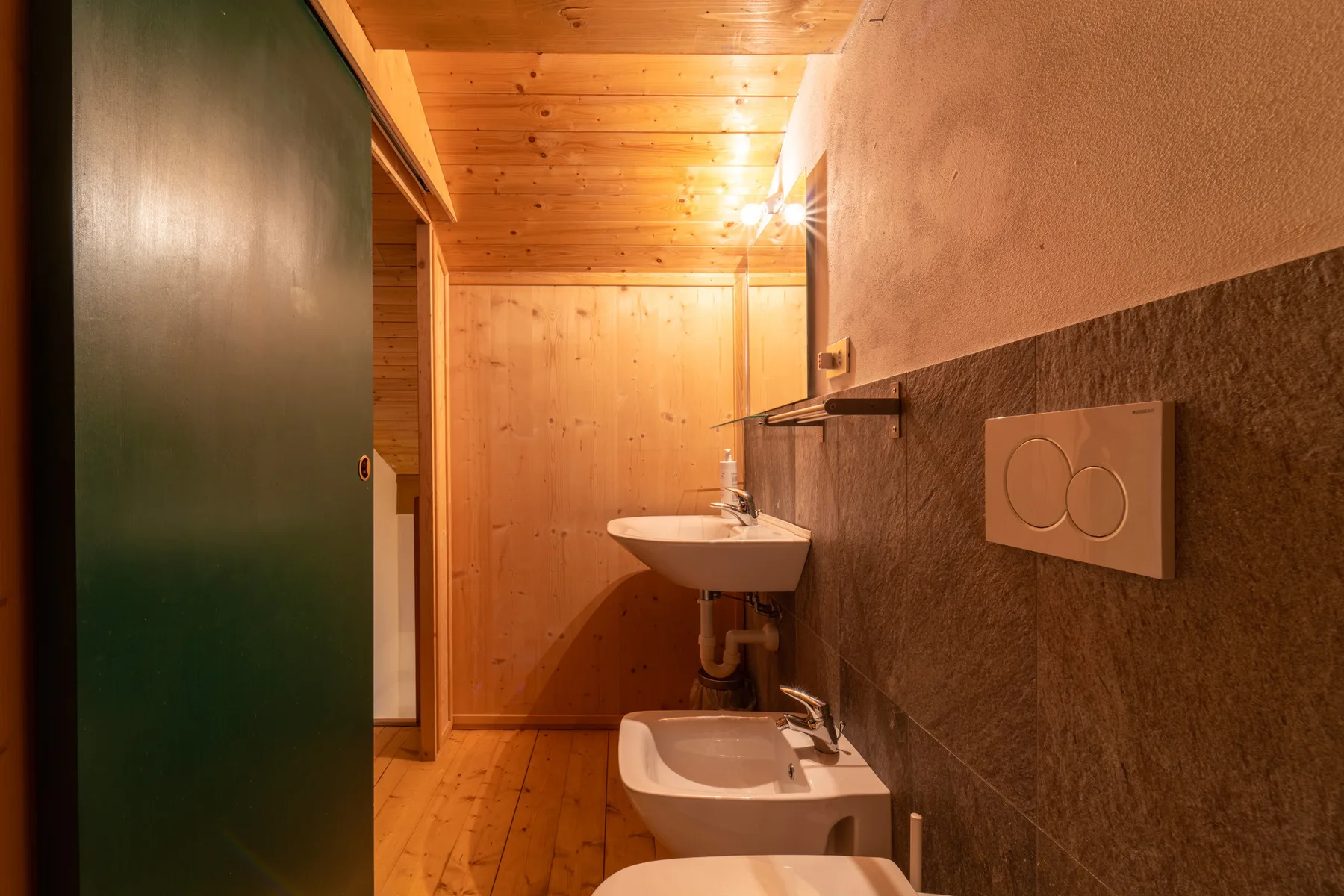 A narrow bathroom with a wall-mounted sink and toilet.