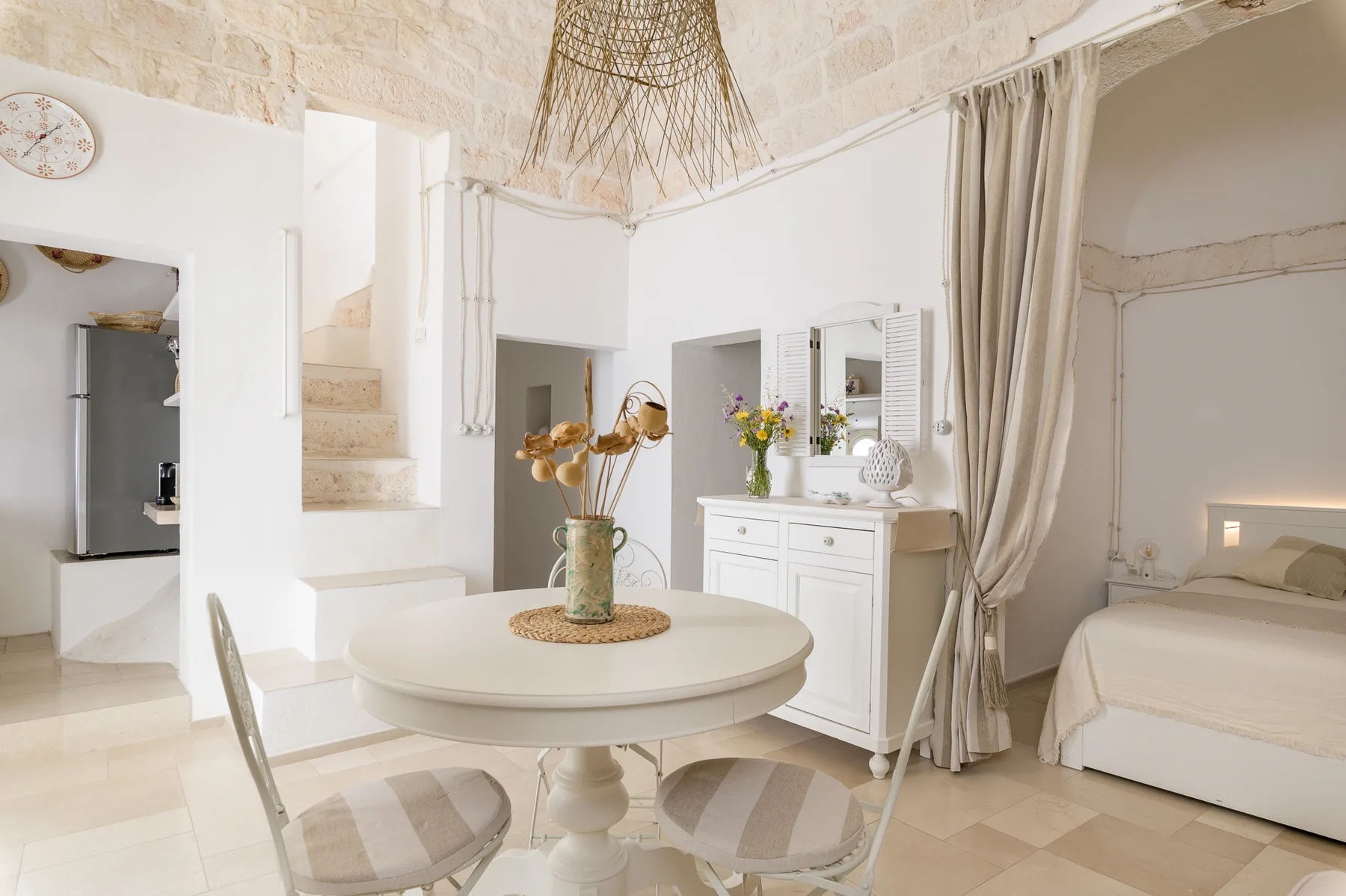 A bright bedroom and sitting area features a round table beside a white dresser.