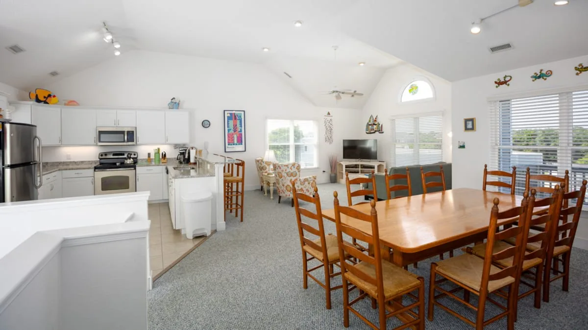 Una cocina abierta al comedor con una mesa de madera y sillas.