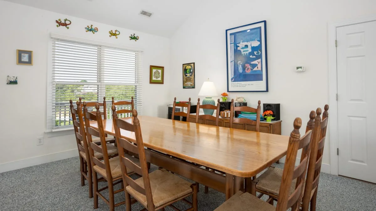 Un comedor con una mesa larga de madera y sillas junto a una ventana.
