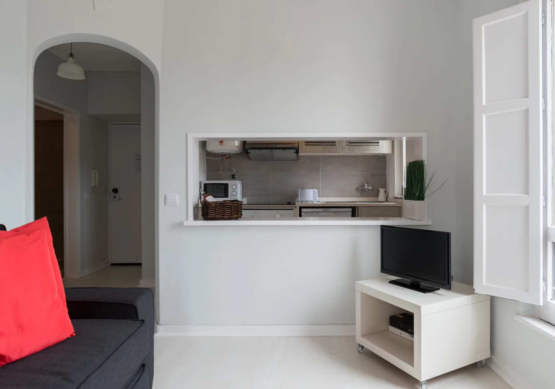 Living area with a kitchen pass-through and television beside the window.