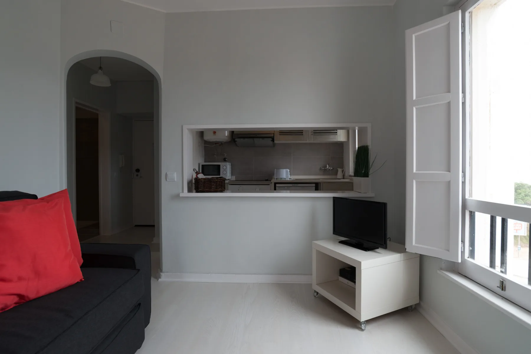 Living room with a kitchen pass-through and a television beside the open window.