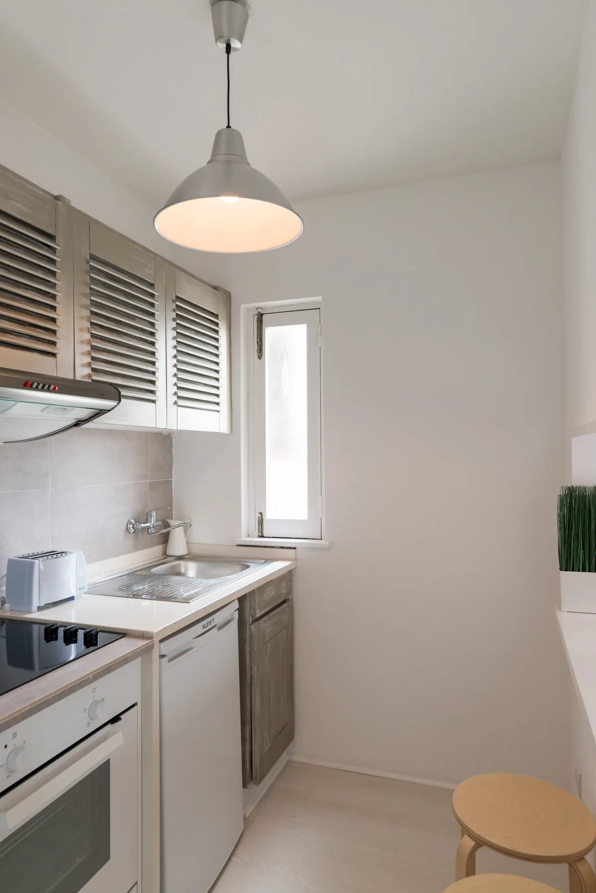 A compact kitchen with a countertop, sink, and small window.