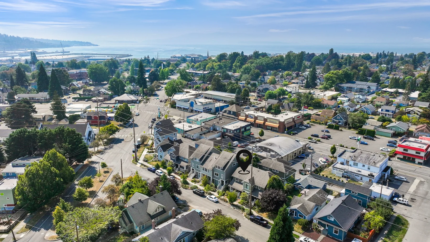 An aerial view of a coastal neighborhood with homes, shops, and water in the distance.