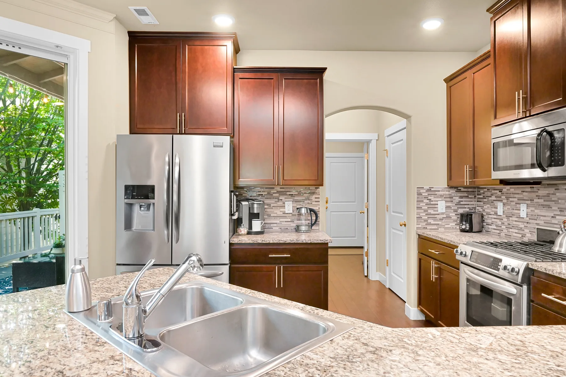 A kitchen with dark wood cabinets, stainless steel appliances, and a sink.