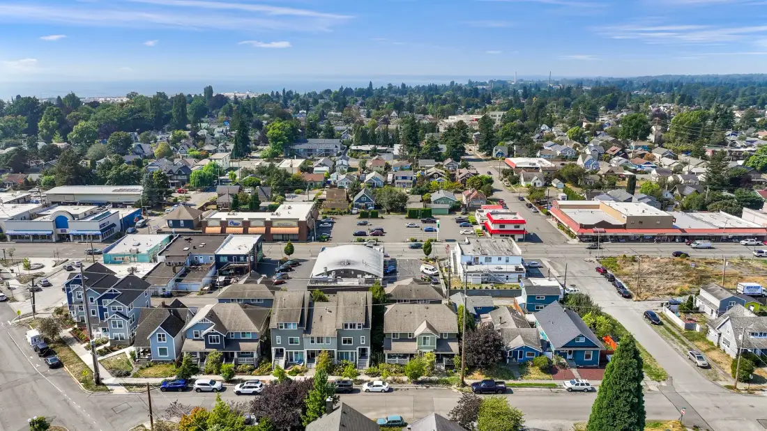 Aerial view of a suburban neighborhood with homes, shops, and tree-lined streets.