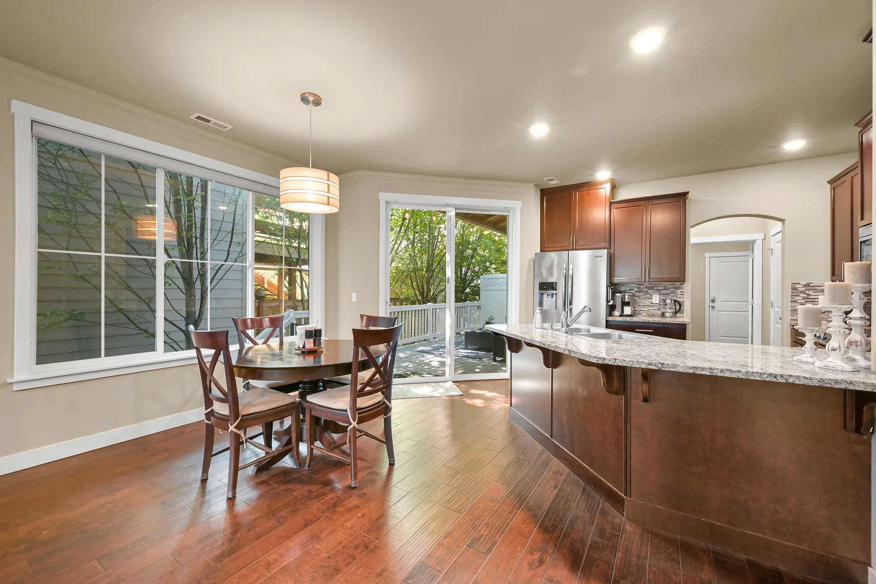 A bright kitchen and dining area with a central island and a table by the windows.