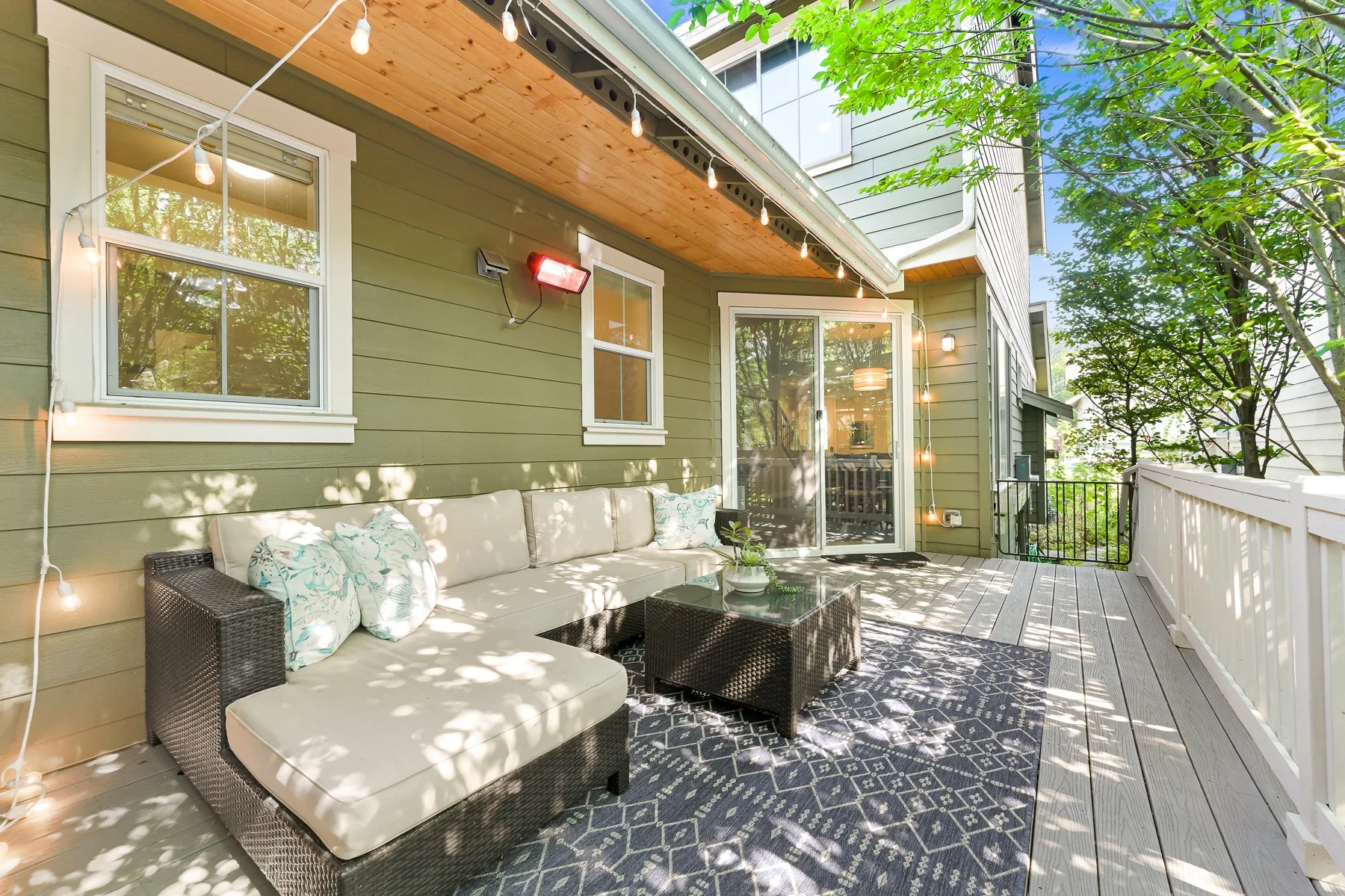 An outdoor deck has cushioned seating beneath a covered wooden overhang.