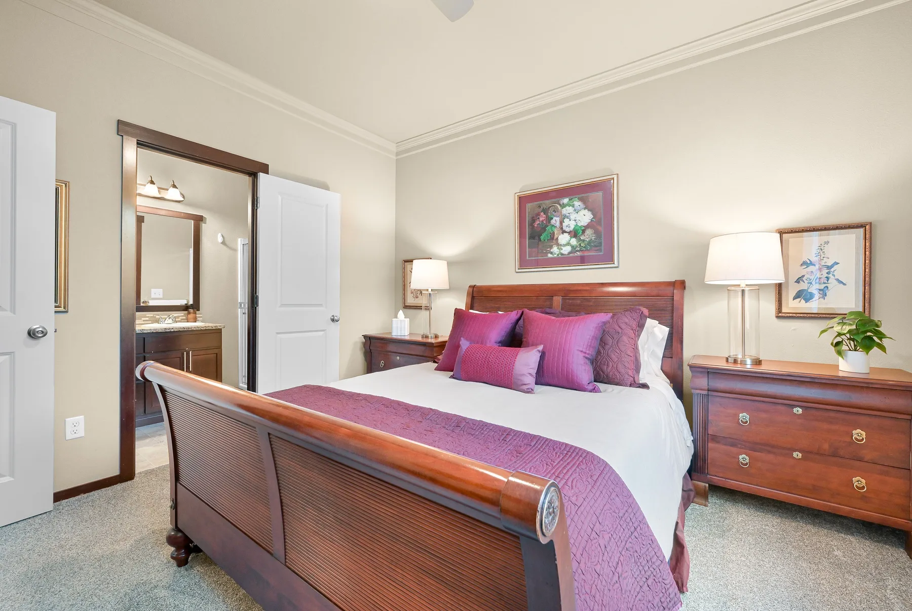 A bedroom with a bed dressed in white and purple bedding.