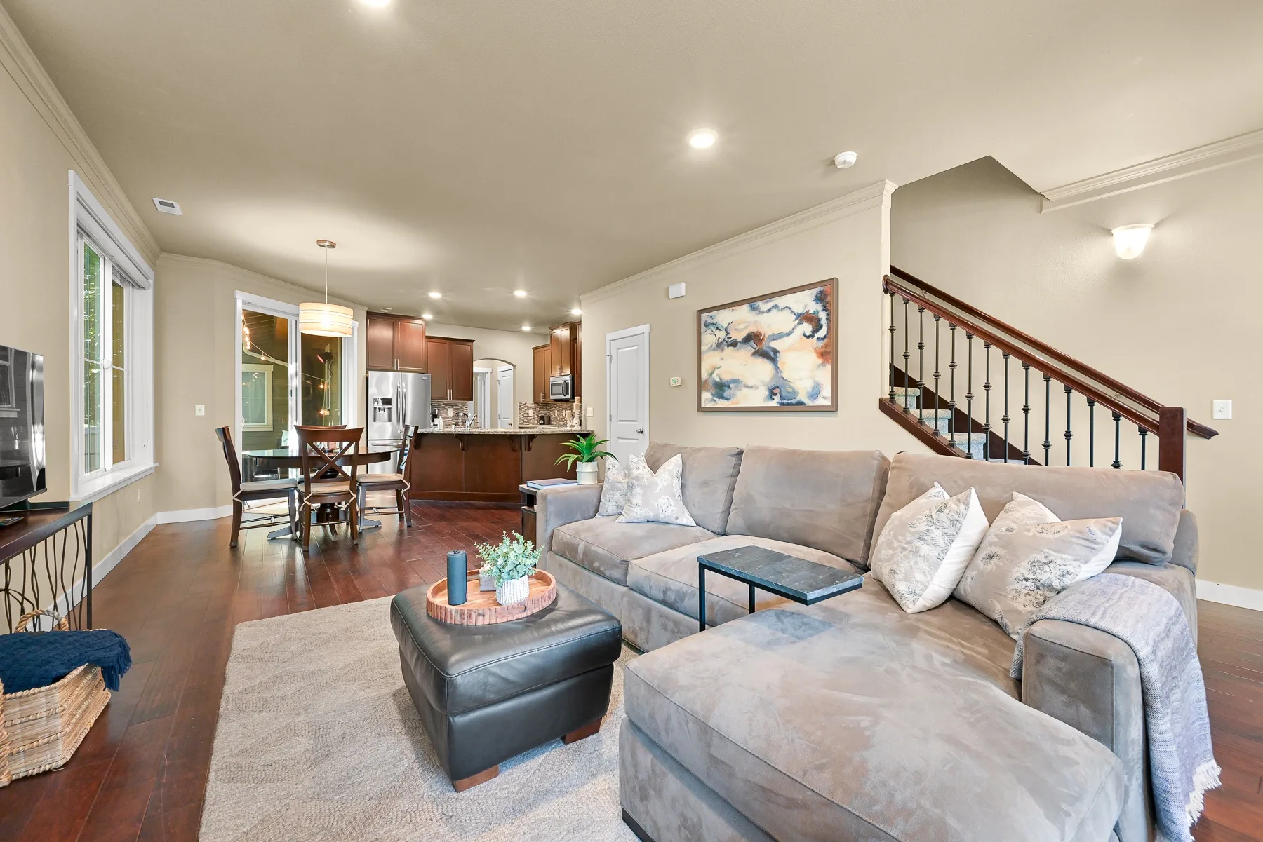Open-plan living room with sectional seating and a kitchen in the background.
