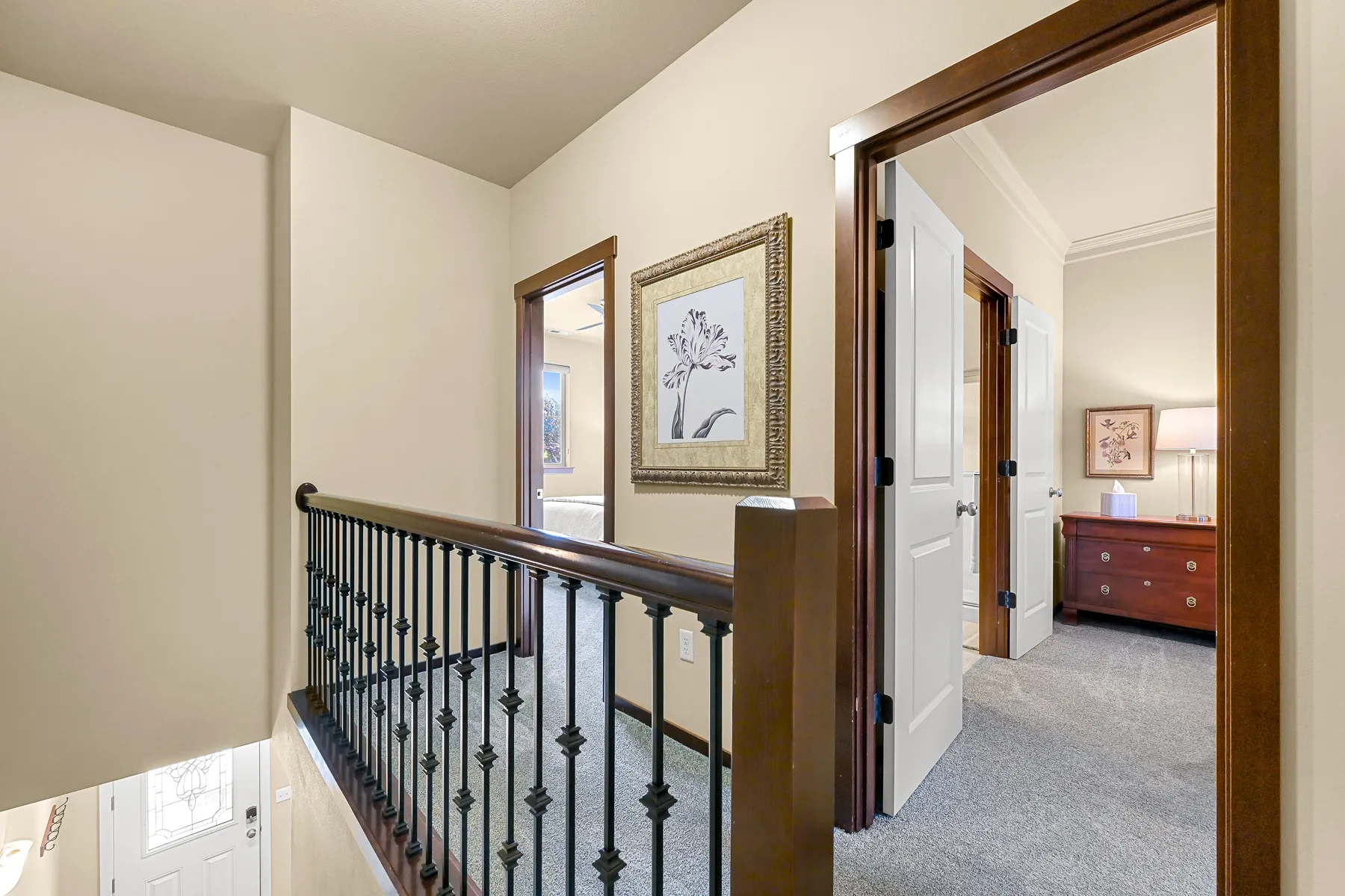 An upstairs hallway with a dark railing and an open doorway.