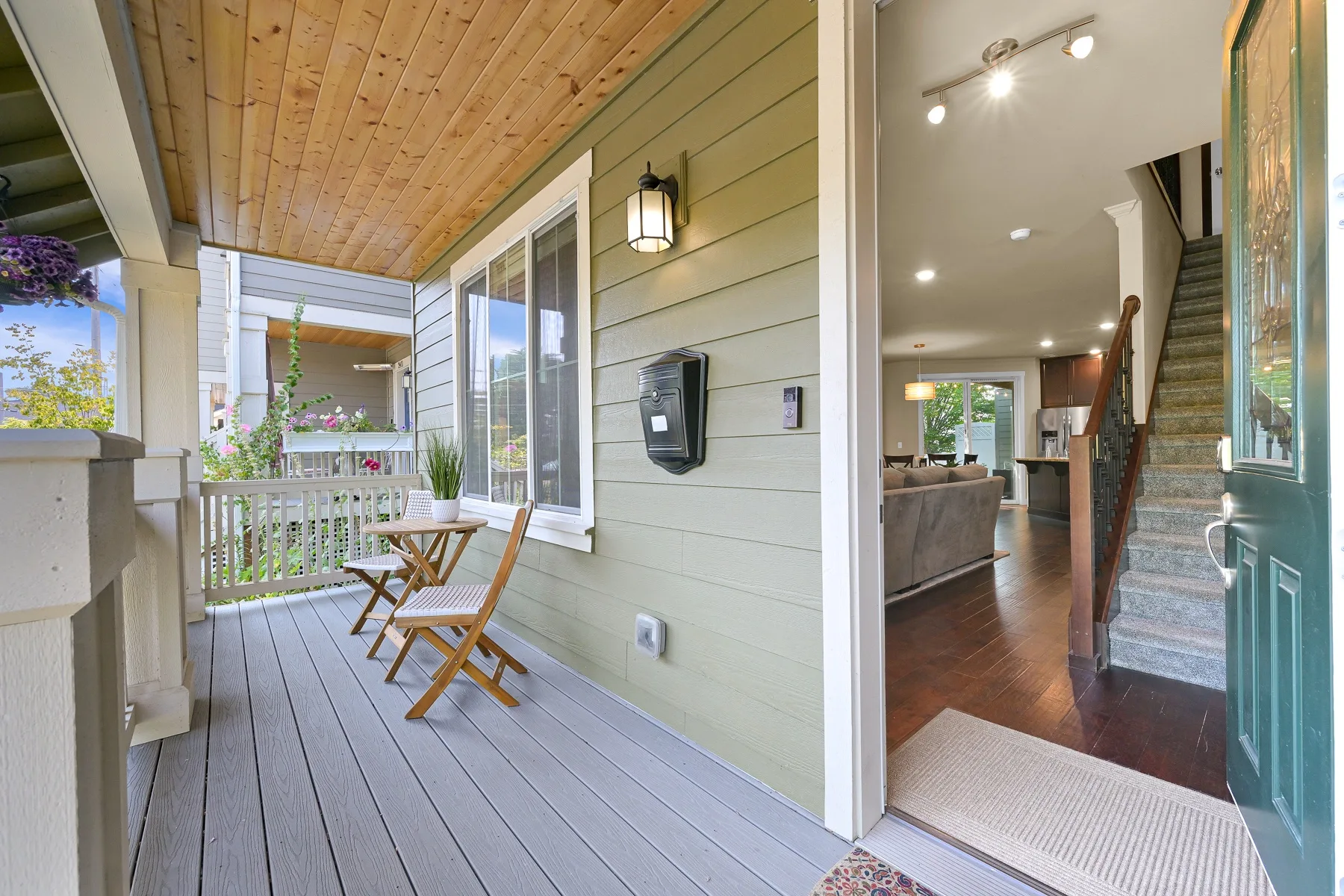 A covered porch with wooden seating opens into an interior hallway and living area.
