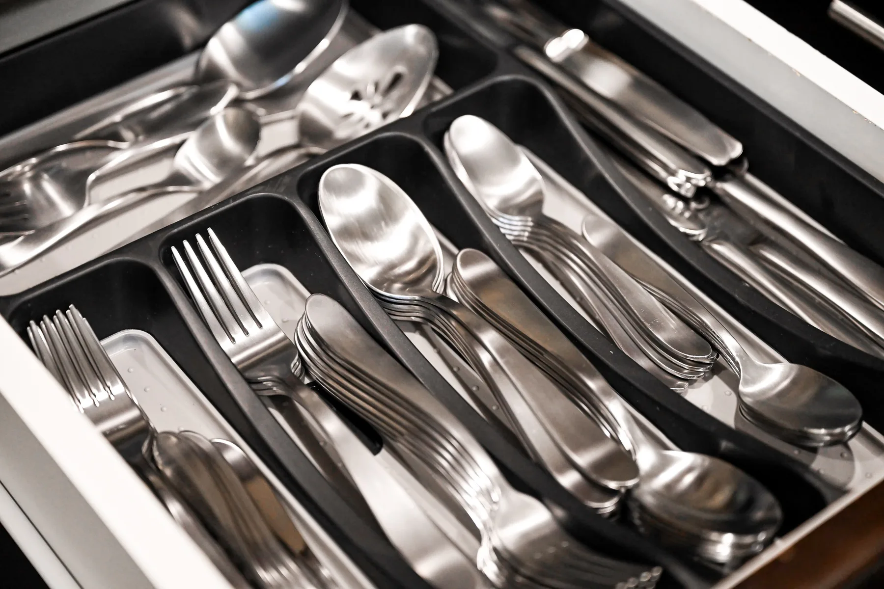A drawer holds organized silverware in divided compartments.
