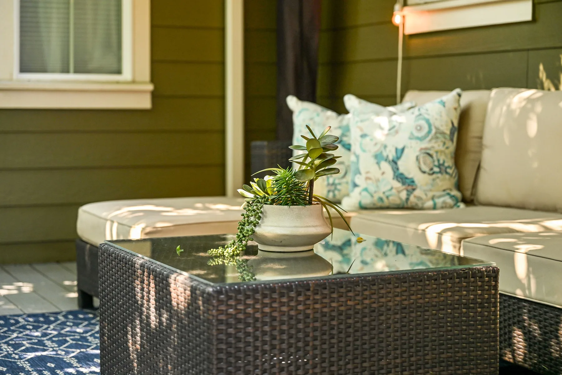 An outdoor seating area with patterned cushions and a low table holding a potted plant.