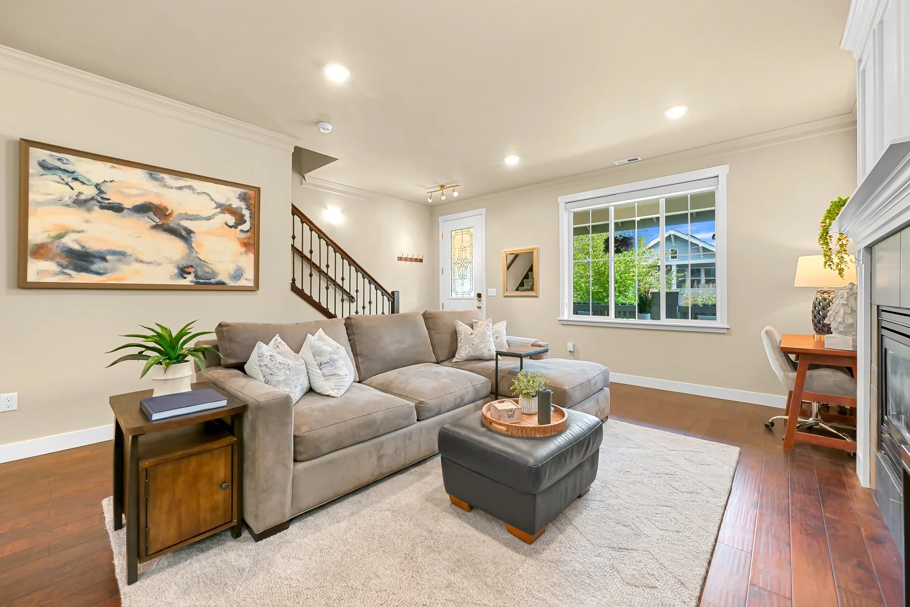 A bright living room with sectional seating, a coffee table, and a large window.