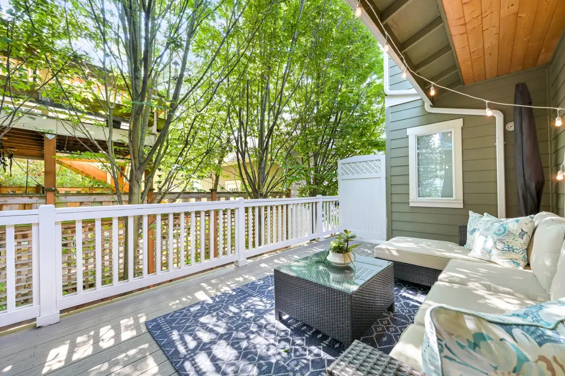 Covered outdoor seating area with a coffee table beside a white railing.