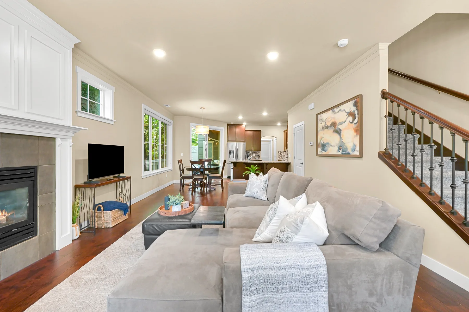 A living room opens toward a dining area, with a sectional and fireplace.